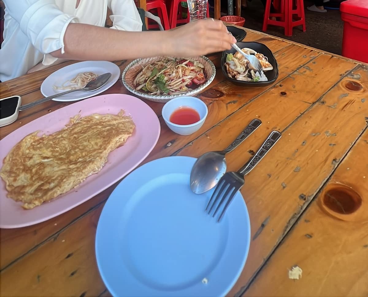Som tam, a Thai omelette and other dishes spread across a wooden table at Lab Charoen