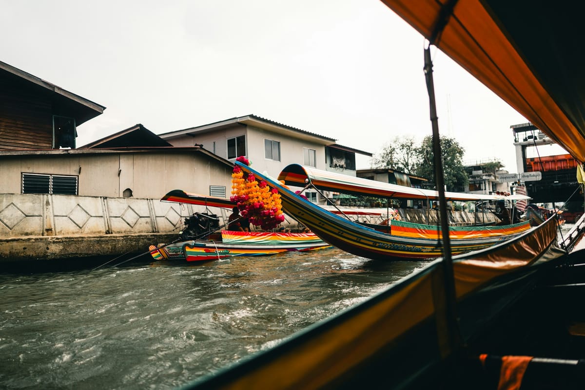 Long-tail boats moored along a Bangkok khlong, seen from the water