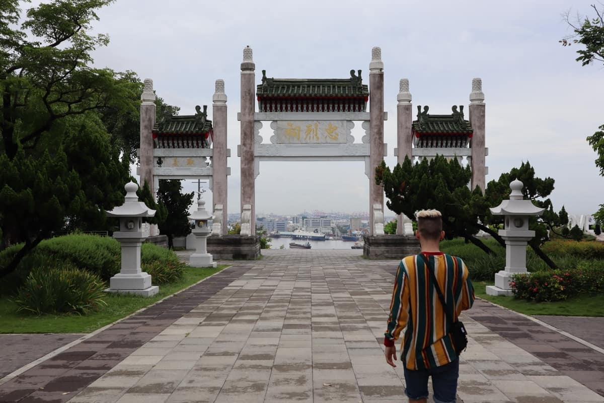 A ceremonial stone gateway at Kaohsiung Martyrs' Shrine framing the harbour below