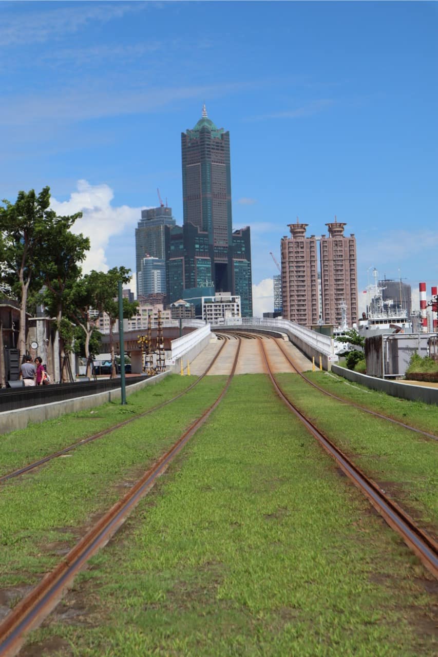Grassy old harbour railway tracks leading towards the 85 Sky Tower in Kaohsiung